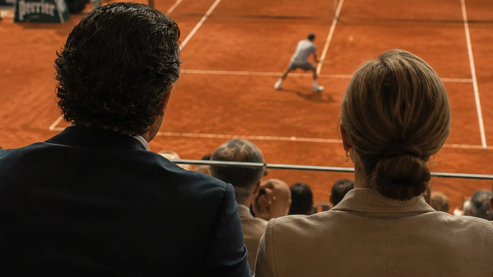Casal assistindo a uma partida de tênis em quadra de saibro